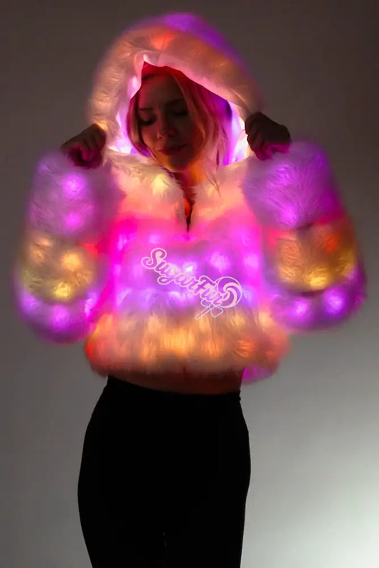 Woman wearing SugarFur Candy Cloud LED Coat illuminated with bright pink, purple, and orange gradient lights for festivals.