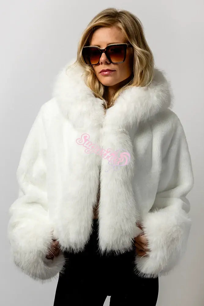 Fluffy white cropped faux fur rave jacket for festival fashion, shown on a blonde model with sunglasses.