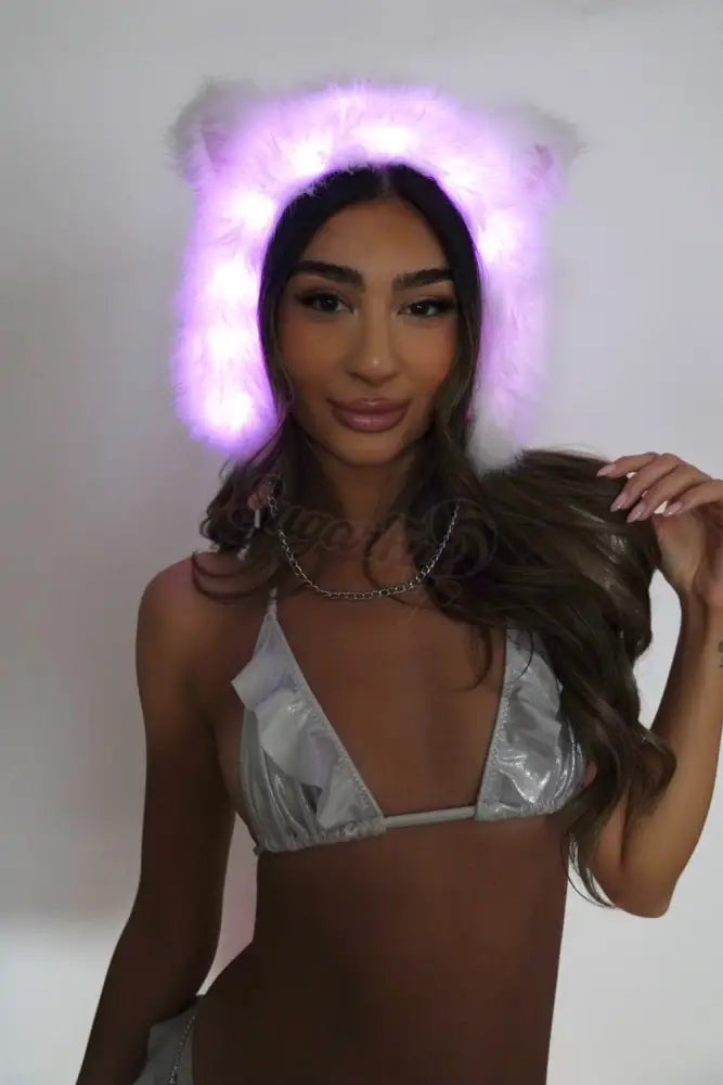 Woman wearing a led fur hat and silver bikini top against a plain background