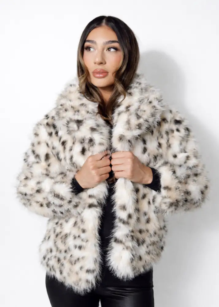 Woman wearing a fluffy leopard white coat with black accents on a white background