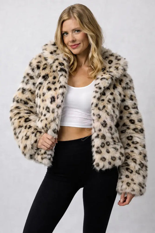 Woman wearing a leopard print fur coat against a plain background